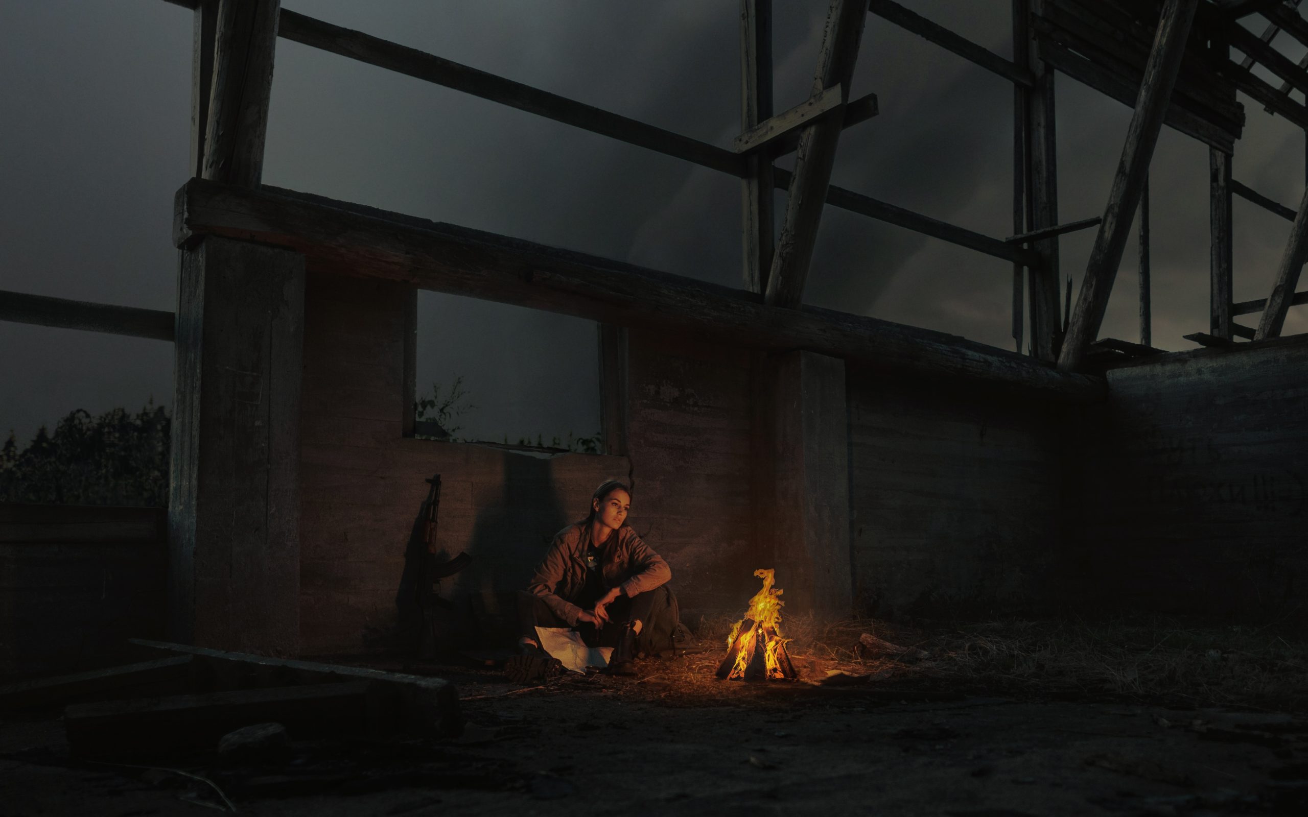 femme devant un feu de camp dans un bâtiment abandonné
